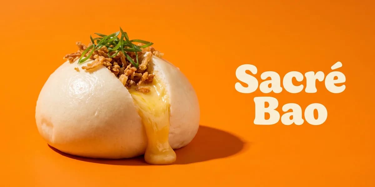 Miniature éditoriale du projet Sacré Bao : un bao vapeur ouvert débordant de munster fondu doré coulant, coiffé d'oignons frits et de cébette, sur fond orange saturé, avec le nom « Sacré Bao » en typo crème arrondie ludique sur le tiers droit